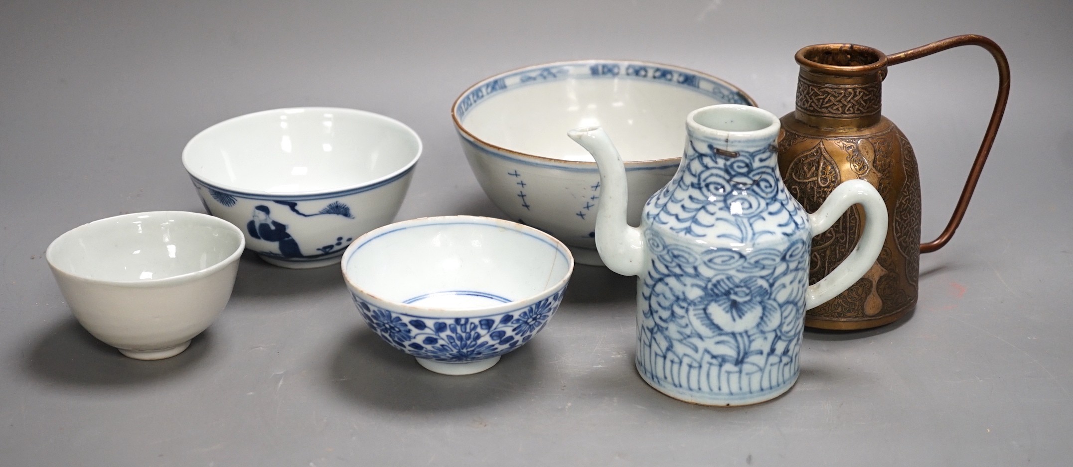 A Chinese Ming dynasty internally decorated porcelain tea bowl, an 18th century blue and white bowl, two other blue and white bowls, a similar water pot and an Islamic brass vessel